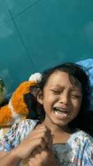 Girl resting against teal wall in Candi, Indonesia