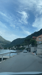White car travels coastal road in Kotor, Montenegro