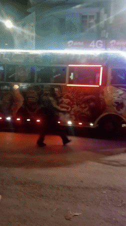 Pedestrian walks past decorated bus in Nairobi street