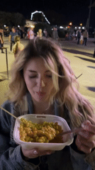 Woman eats pasta outdoors at night in Bar, Montenegro