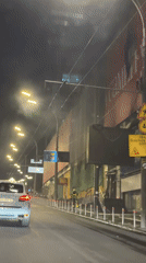 White SUV passes smoke and tarp-covered building in Kyiv night