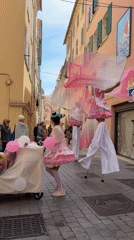 Stilt performers in cotton candy costumes parade through Toulon streets