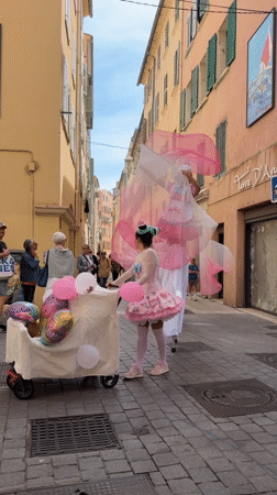 Stilt performers in cotton candy costumes parade through Toulon streets