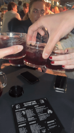 Friends toast with drinks at outdoor Biarritz restaurant