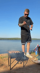 Man grills lakeside in Chaikovsky, Russia