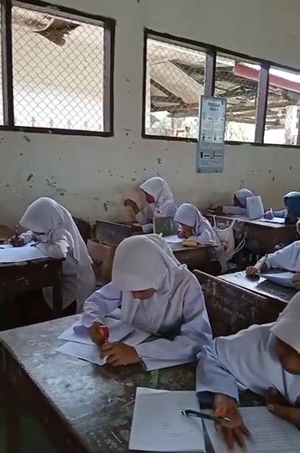 Students study in Indonesian classroom during early morning hours