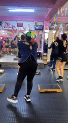 Step aerobics class underway at a pink Lima fitness studio