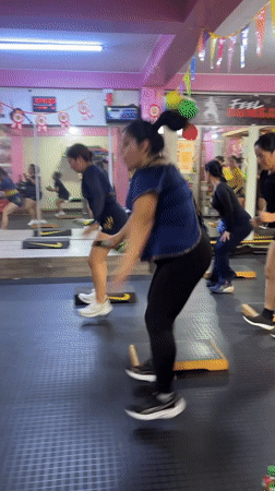 Step aerobics class underway at a pink Lima fitness studio