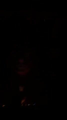 A person is standing behind a DJ booth in a dark room, illuminated by a red spotlight. The person is obscured by shadows and appears to be mixing music. The spotlight is positioned above and to the right of the person, casting a dramatic beam of red light across the scene. Several other red lights are visible in the background, suggesting a nightclub or concert setting. The video is brief and focuses on the atmosphere of the performance.