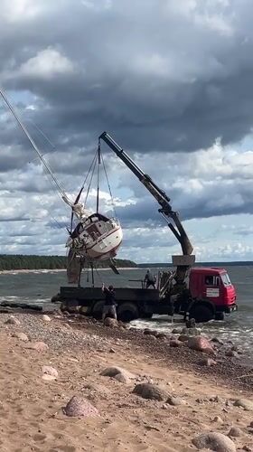 Sailboat hauled out of the water by beach crane truck