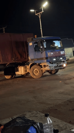 Commercial trucks stop in Bukuru as street vendors operate