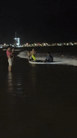 Night swim session off Da Nang beach with city lights behind
