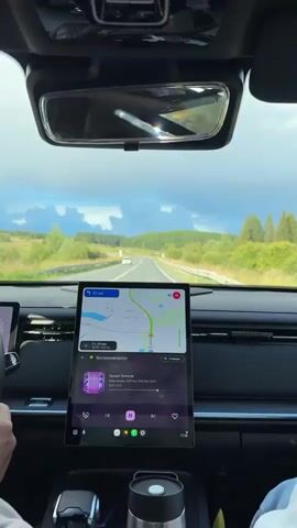 The video shows the view from the driver's seat of a car traveling on a highway. The dashboard display shows a navigation map with a route highlighted and the remaining distance to the destination as 41 kilometers. The map also indicates the estimated travel time is 2 hours and 44 minutes, and the total distance of the trip is 202 kilometers. Below the map, a music player is visible, displaying the song title "Sunset Slammer" and genre information. The road ahead curves to the right, with trees and fields on either side, and a cloudy sky above. The car is moving, and the scenery is passing by.