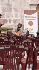 Street musician plays acoustic guitar with sheet music outdoors