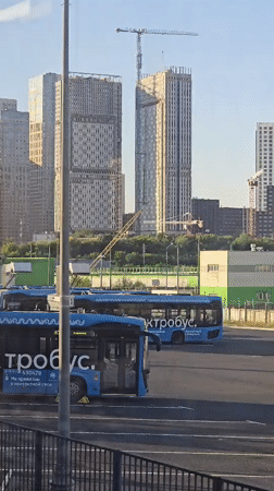 Trolleybuses, a Russian flag, and freight trains on an afternoon.