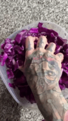 Tattooed person prepares red cabbage dish in Buenos Aires kitchen