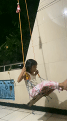 Girl plays on homemade zip line and swing in Gelam