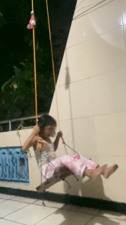 Girl plays on homemade zip line and swing in Gelam