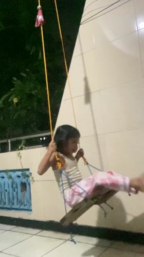 Girl plays on homemade zip line and swing in Gelam