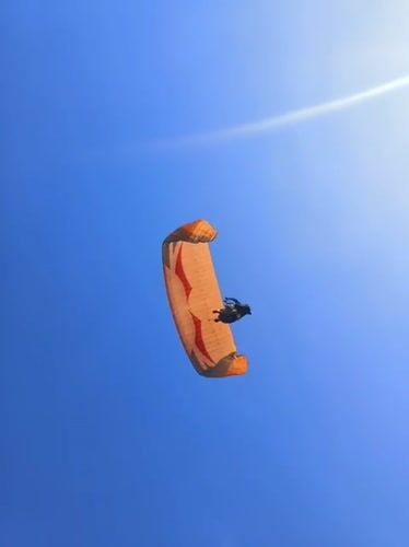 Tandem paragliders fill the sky above Kuta Selatan's coastline