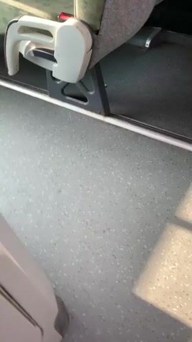 The video captures the interior of a bus with empty seats. The camera pans across the seats and then through the front windshield. Outside, another bus is visible, and a person is walking on a sidewalk. The footage appears to be recorded by someone on the bus, looking out.