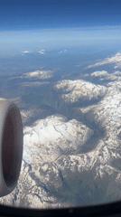 Passenger films mountainous landscape from airplane window over UK