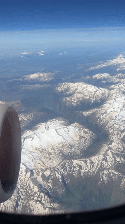 Passenger films mountainous landscape from airplane window over UK