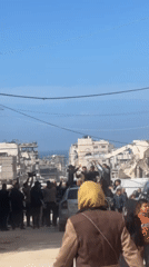 Men celebrate amid Gaza ruins, formal-dressed figure carried