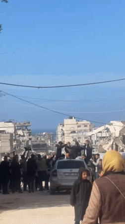 Men celebrate amid Gaza ruins, formal-dressed figure carried
