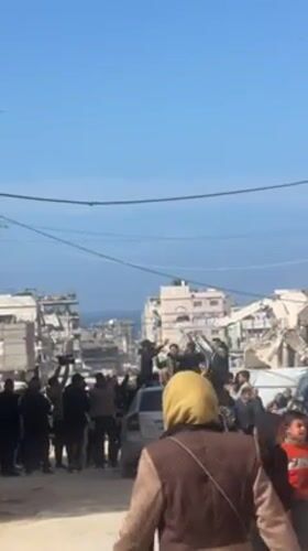 Men celebrate amid Gaza ruins, formal-dressed figure carried