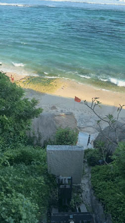 Woman sunbathes on mossy rocks at Ungasan beach resort