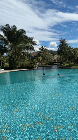 Swimmers captured at Chalong resort pool during sunny afternoon