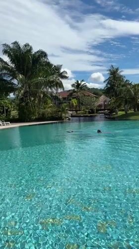 Swimmers captured at Chalong resort pool during sunny afternoon