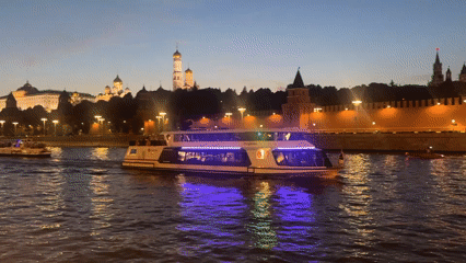 Passenger boat passes the Kremlin on the Moscow River at dusk