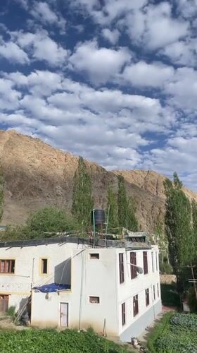 White building with prayer flags in Leh's mountain landscape
