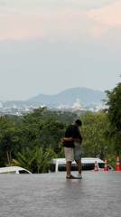 Couple embraces at scenic overlook during Wichit evening market