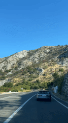 Gray hatchback navigates Montenegro's winding coastal cliff road