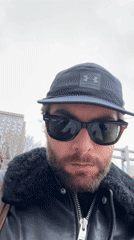 Person takes selfie in Montreal wearing baseball cap and sunglasses