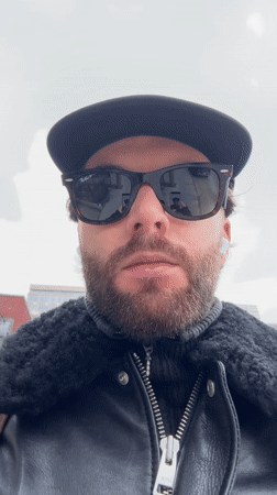 Person takes selfie in Montreal wearing baseball cap and sunglasses