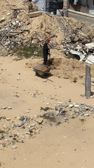 Man with wheelbarrow clears debris in Khan Yunis