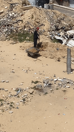 Man with wheelbarrow clears debris in Khan Yunis