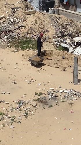 Man with wheelbarrow clears debris in Khan Yunis