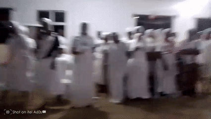Religious gathering features group singing, dancing in white robes