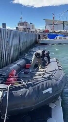 Person prepares inflatable boat at Ushuaia marina on clear day