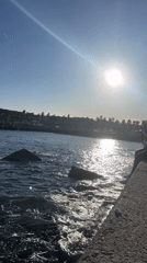 Person sits on Barcelona waterfront ledge during sunny afternoon
