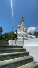 Woman descends temple stairs near Buddha statue in Thailand