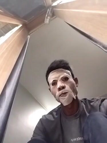 Person in white sheet mask documented during Indonesian rainstorm
