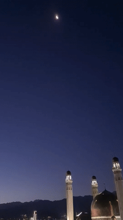 Almaty mosque glowing under a moonlit evening sky