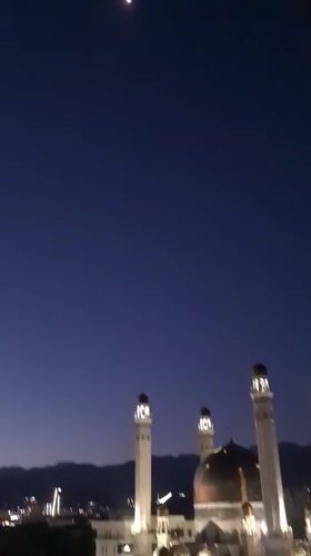 Almaty mosque glowing under a moonlit evening sky
