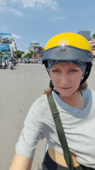 Woman rides scooter through sunny Hà Nội streets
